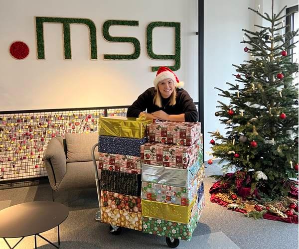 Danke an alle, die so tatkräftig unterstützt haben! Mitarbeiterin beugt sich über einen Stapel mit Geschenken und lächelt.