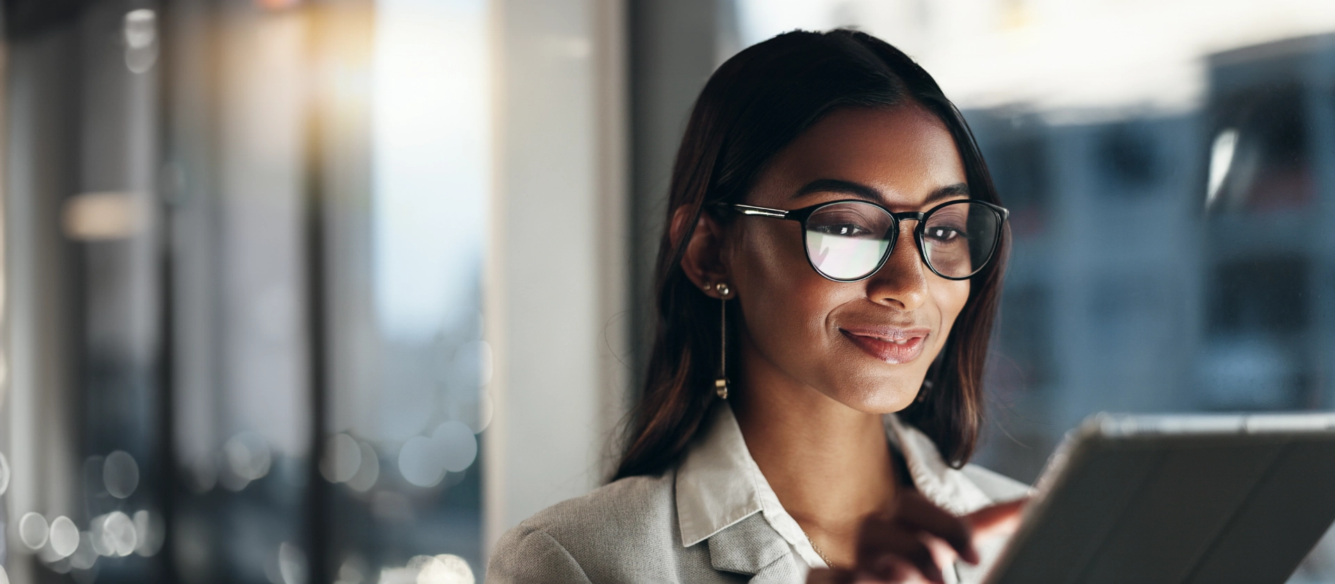 Frau mit Brille liest Tablet und lächelt