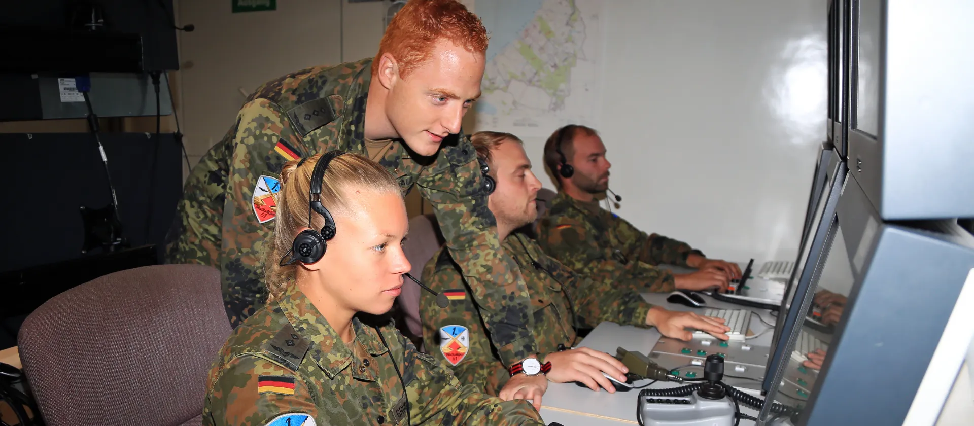Gemischte Gruppe von Soldaten und Soldatinnen an einem Schreibtisch am PC