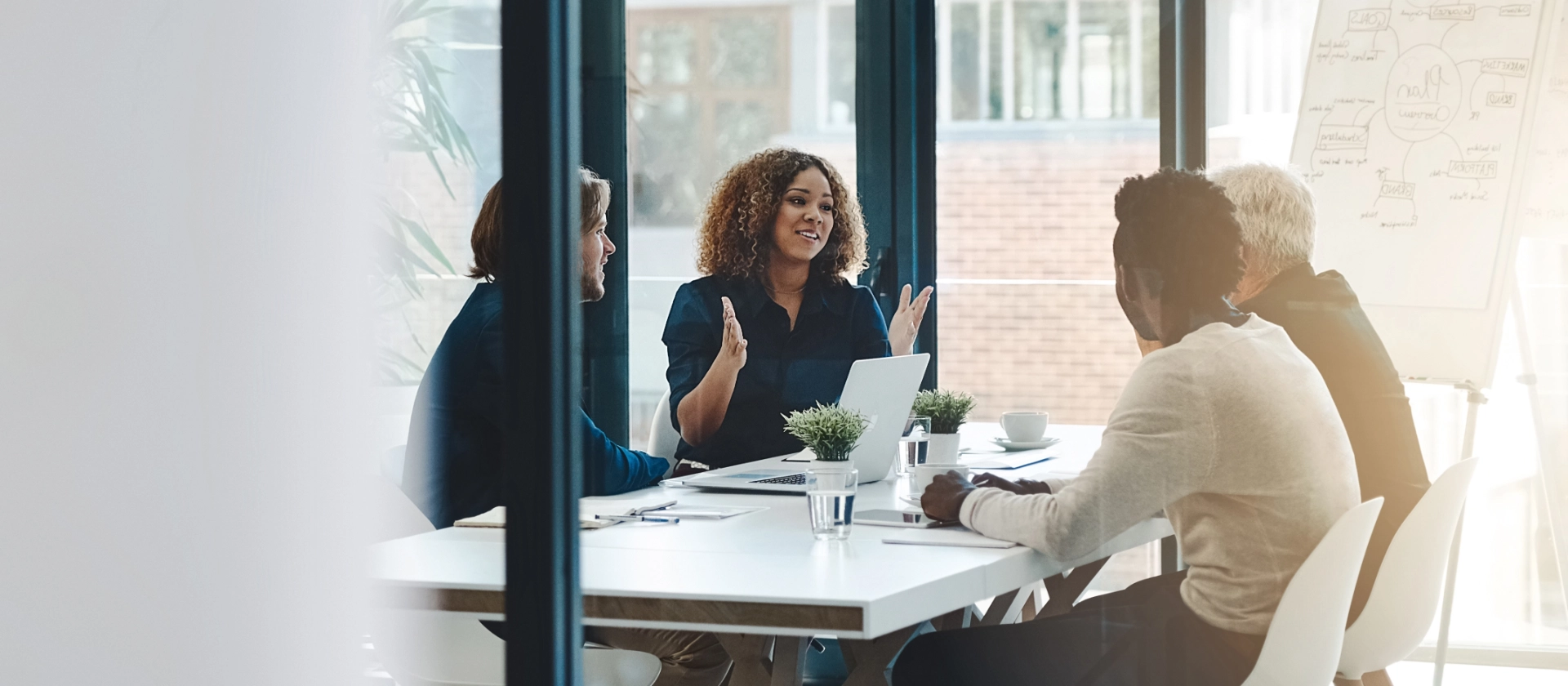 Geschäftstreffen mit vier Personen im modernen Besprechungsraum, Fokus auf Zusammenarbeit und Strategie.