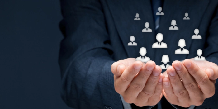 Symbolic image for AML customer segmentation: Businessperson holding abstract customer icons in cupped hands – representing protection and dynamic clustering for improved anti-money laundering monitoring.