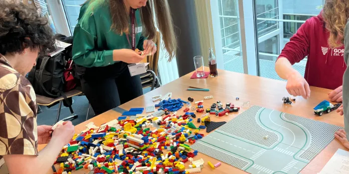 Studierende Teilnehmende des Scrum-Trainings setzen LEGO-Steine zusammen