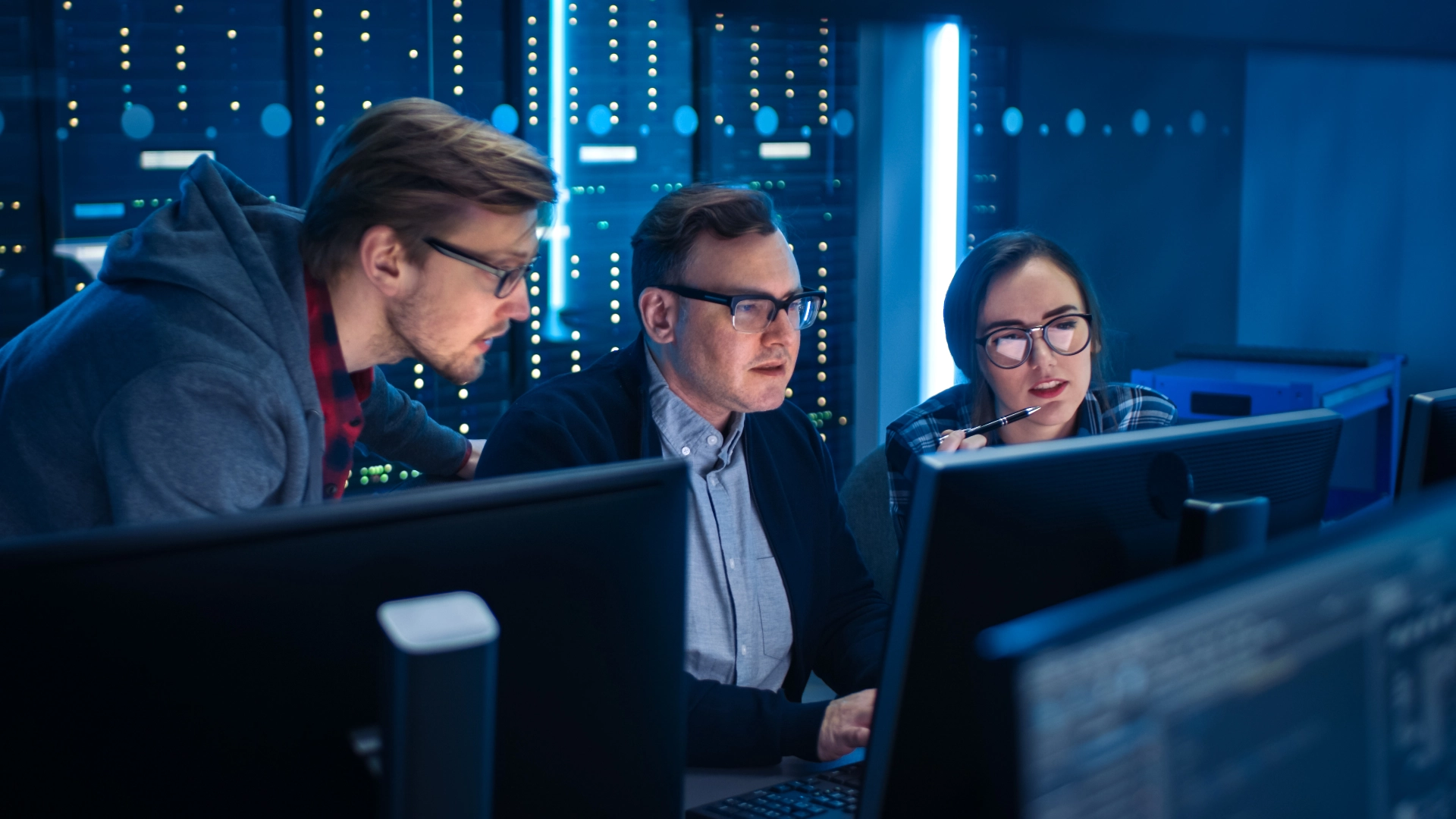 Zwei Kollegen und eine Kollegin aus dem Bereich Cyber Security sitzen konzentriert an einem Arbeitsplatz vor ihren Rechnern